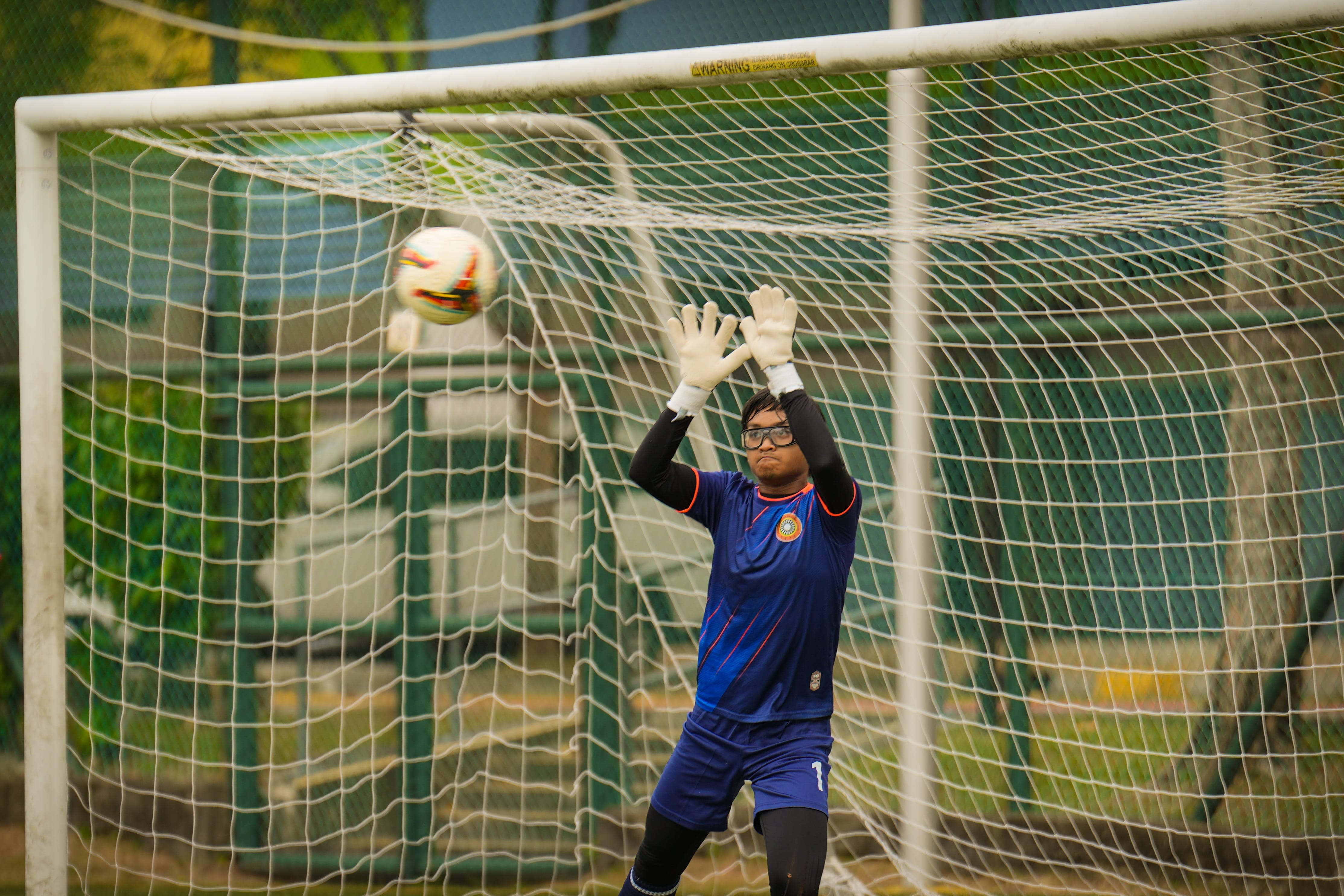A goalkeeper catching a ball during a match